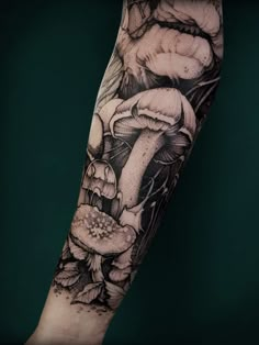 an arm tattoo with mushrooms and flowers on it