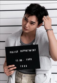 a young man holding up a sign in front of his mugshot muggy face