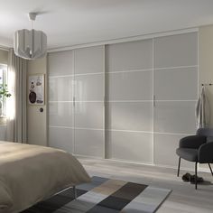 a bedroom with a bed, chair and sliding closet doors