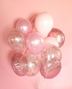 a bunch of balloons that are in the shape of hearts on a pink background with silver foil