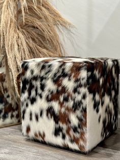 a brown and white animal print box sitting on top of a wooden table next to a plant