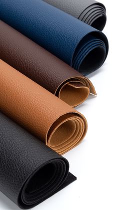 four different colors of leathers on a white surface with one rolled up and the other rolled down