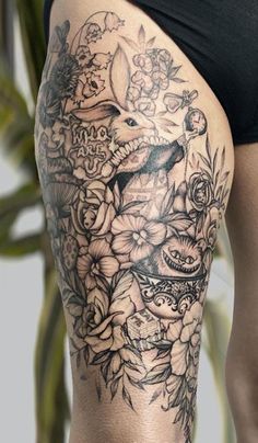 a woman's thigh with tattoos and flowers on it