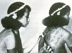 two women with tattoos on their body and one has her hair combed back to the side