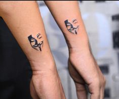 two people holding hands with tattoos on their arms