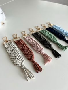 six different colors of tasselled key chains on a table with a white cloth