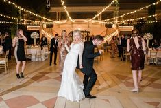 a bride and groom dance together at their wedding reception in an indoor venue with string lights