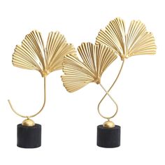 two gold leaf sculptures sitting on top of black bases