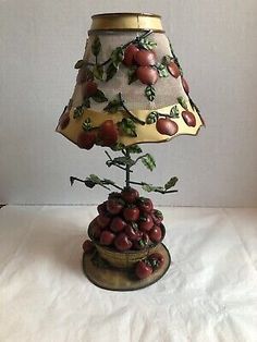 a lamp with fruit on it sitting on top of a white cloth covered tablecloth