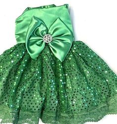 a green dress with sequins and a large bow on the front, sitting on a white surface