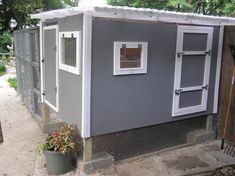 a small gray shed with two windows on the side