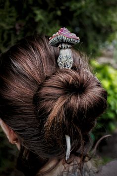 the back of a woman's head with a mushroom hair clip in her hair