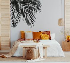 a bed with pillows and blankets on it in front of a palm tree wall mural