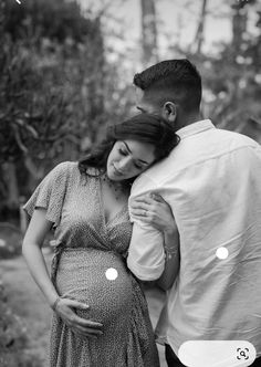 a pregnant woman hugging her husband in the woods