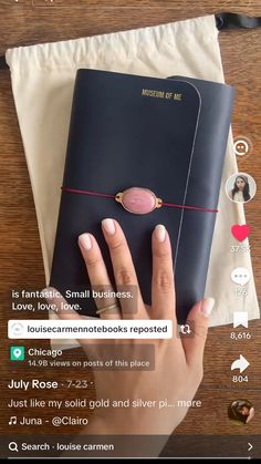 a woman's hand is holding a black book with pink decorations on it, and the text reads