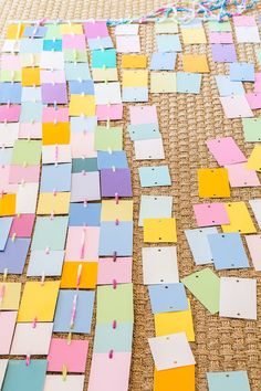 many pieces of colored paper are laid out on the floor with pins stuck to them