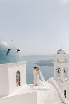 a bride and groom standing on the roof of a church in front of an ocean