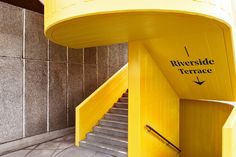 stairs leading up to the top of a yellow structure with riverside terrace written on it