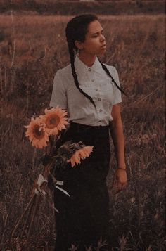 a woman standing in a field holding flowers