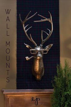 a metal deer head mounted to the side of a wall next to a potted plant