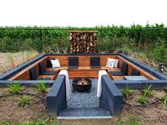 a fire pit surrounded by wooden benches in the middle of some grass and dirt area