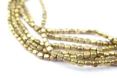 three strands of gold colored beads on a white background