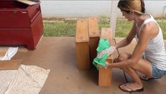 a woman is sitting on the ground next to some wooden benches and boxes with cloths