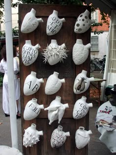 many white vases are on display in front of a wooden board with numbers and symbols