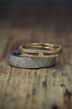 two gold and silver wedding bands on top of each other with a diamond in the middle