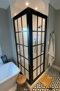 a bathroom with a black and white tiled floor, glass shower stall and bathtub