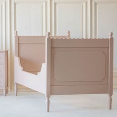 a pink bed with two nightstands in front of the headboard and foot board