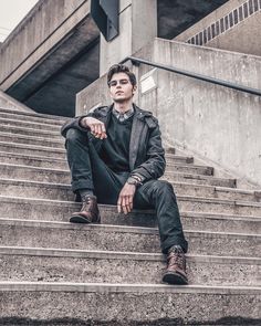 a young man sitting on the steps in front of a building