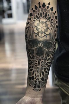 a man's arm with a skull and geometrical design on the left forearm