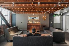 a man sitting on top of a couch in a living room next to a bar