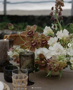 a table topped with lots of white and brown flowers next to candles on top of a wooden table