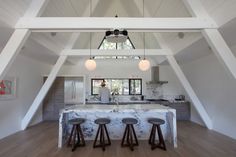 an open kitchen with marble counter tops and bar stools in the middle of the room