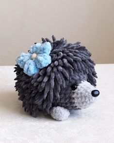 a small stuffed animal with a flower on its head sitting on a white table top