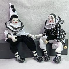 two dolls sitting next to each other on a shelf