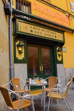 the outside of a restaurant with tables and chairs in front of it, next to a lamp post