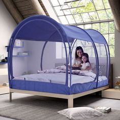 a child's bed with a blue canopy over it and a woman holding a baby