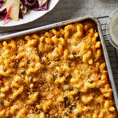 a casserole dish with macaroni and cheese on it next to a salad