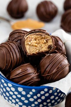 a blue bowl filled with chocolate covered peanut butter truffles and one cut in half