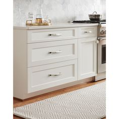 a kitchen with white cabinets and an area rug