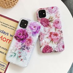 two phone cases sitting on top of a white table next to a bag and purse