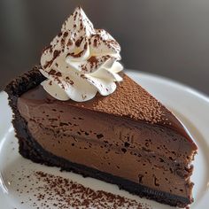 a piece of chocolate cheesecake on a white plate with whipped cream and sprinkles