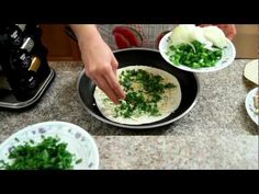 someone is preparing food in a skillet on the kitchen counter with other plates and utensils