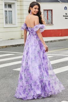 a woman in a purple dress is standing on the street with her back to the camera