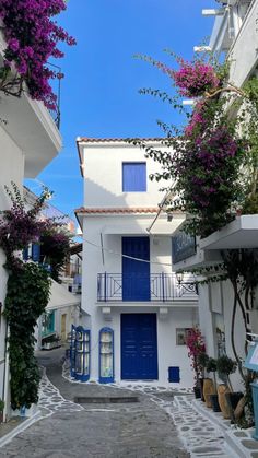 an alleyway with white buildings and blue doors in the village of mykonos, greece