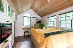 a bed in a room with wooden ceiling and white walls, along with two windows