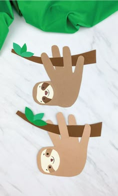 two paper slots hanging from a tree on a marble counter top with green leaves